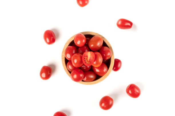 Top view of cherry tomatoes in a wooden bowl isolated on white background Top view of cherry tomatoes in a wooden bowl isolated on white background grape tomatoes stock pictures, royalty-free photos & images