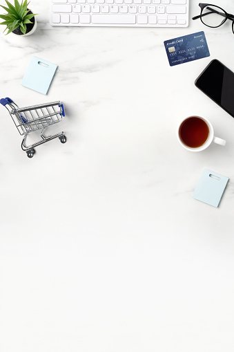 Top view of online shopping concept with credit card, smart phone and computer isolated on office marble white table background.