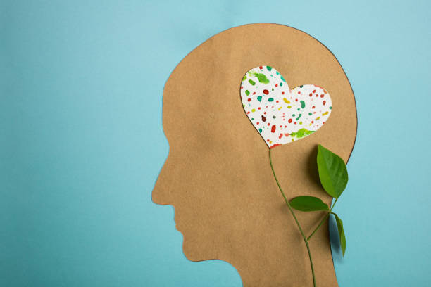 World Heart and Mental Health Day. Paper Cut as Human Head with Leaf Tree and Colorful Heart Shape Flower inside the Brain. Psychology, Creativity and Positive Mind Concept stock photo