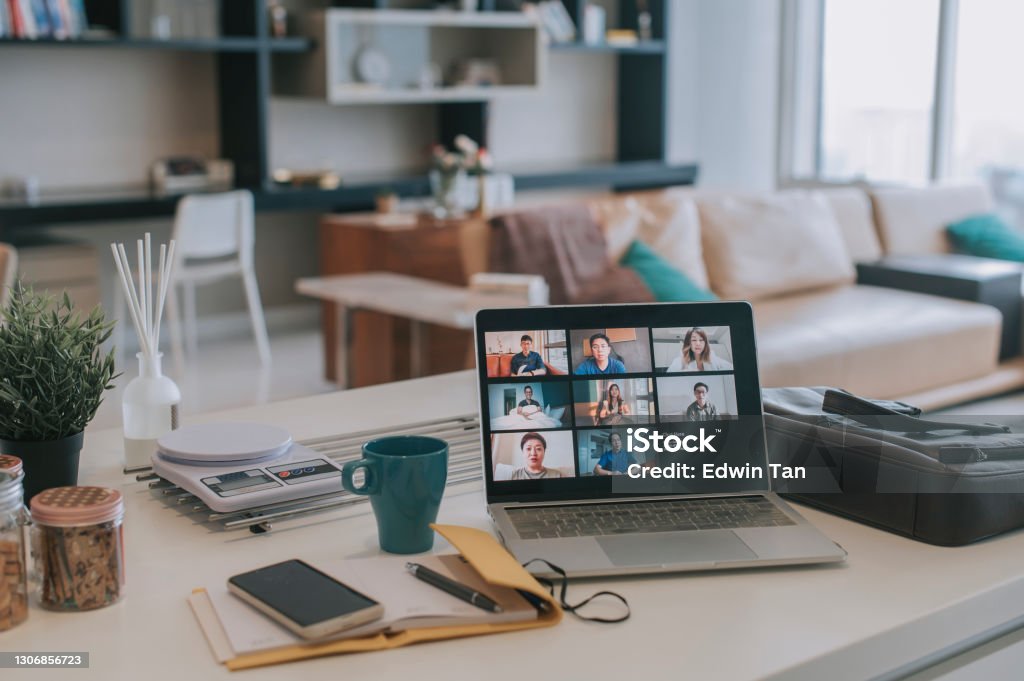 laptop with screen video conference on kitchen counter with smart phone , note pad Working At Home Stock Photo