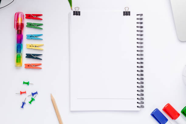 istock Top view on working space with a white notebook with free space for text in the center 1306857008