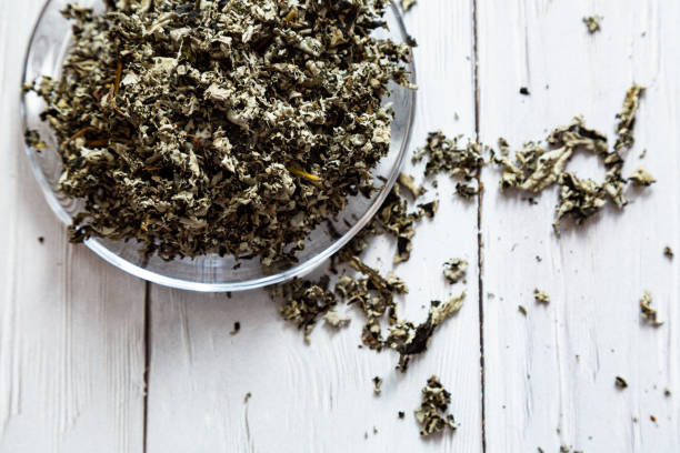 istock Fermented tea made from raspberry leaves in a glass plate on a white wooden table. Composition with organic, natural, dry herbal tea 1306857067