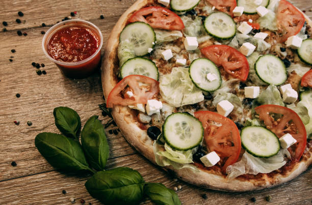 istock Vegetable pizza with mozzarella, fresh tomatoes and cucumber. Green basil leaves 1306857189