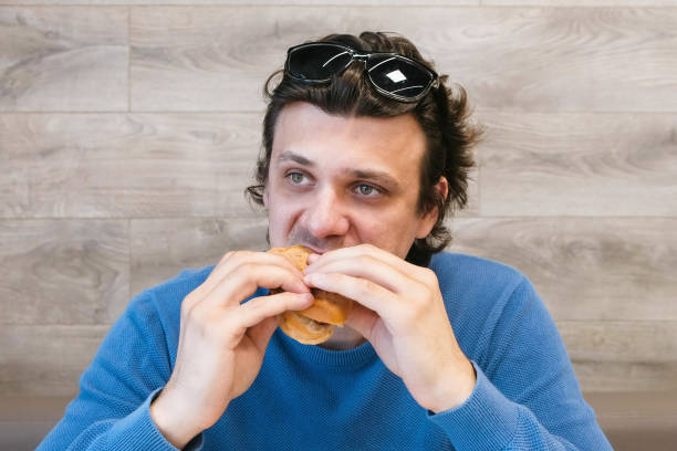 istock Man is eating a hotdog in cafe. 1306858085