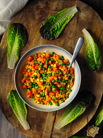 Homemade stir-fried diced carrot with garden peas, sweet corn, spring onion service with cos lettuce