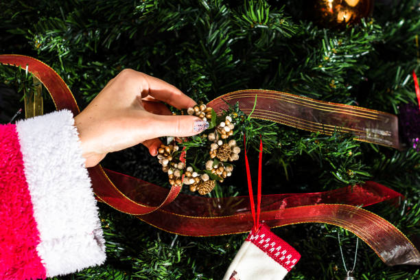 istock Decorating Christmas tree, hand putting Christmas decorations on fir branches. Christmas hanging decorations. 1306860039