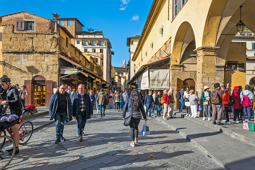 FLORENCE, ITALY - MAY 09, 2019: Old Bridge Ponte Vecchio in Florence, Vasari corridor adjacent to the Old Bridge that leads to the Uffizi is always very busy with tourists that stroll and take photos at Ponte vecchio.