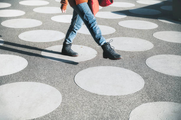 young  woman walking white spotted town square girl going on asphalt town square with white dots in berlin in the afternoon sun fashion photography color image colors stock pictures, royalty-free photos & images