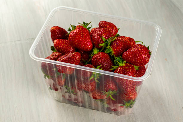 istock a clear plastic container with ripe juicy red strawberries is on table 1306871899