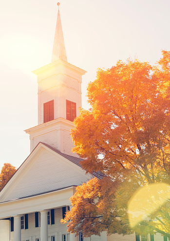 Traditional American white church in the fall with natural sun flare