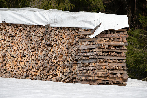Stack of chopped firewood covered with plastic to protect from rain.