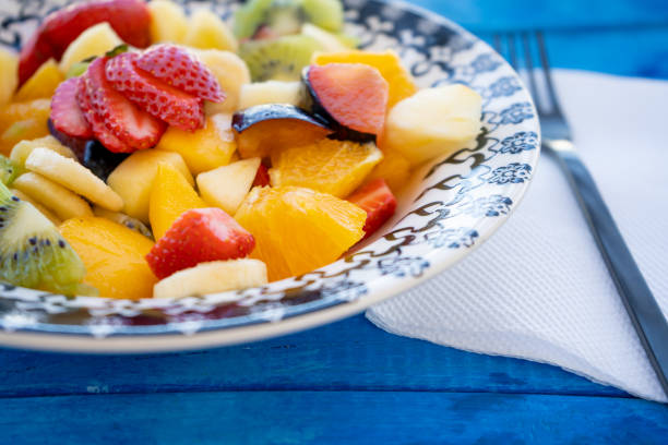 istock Natural and healthy fruit salad with orange set in a vintage plate on a rustic blue surface. Healthy Food Concept, Healthy Life. 1306876783