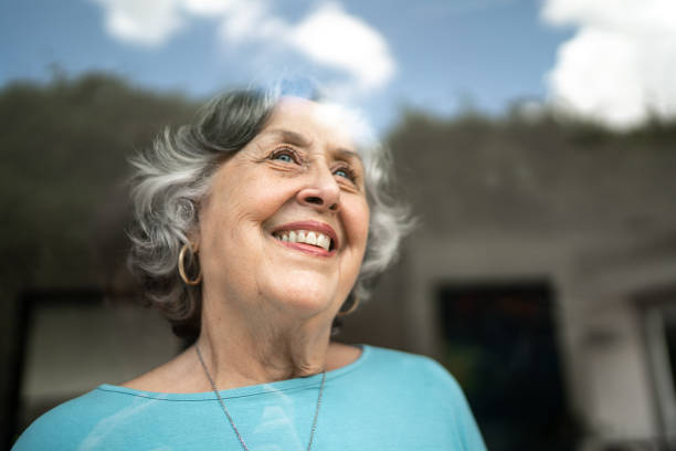 istock Senior woman looking through window at home 1306876899