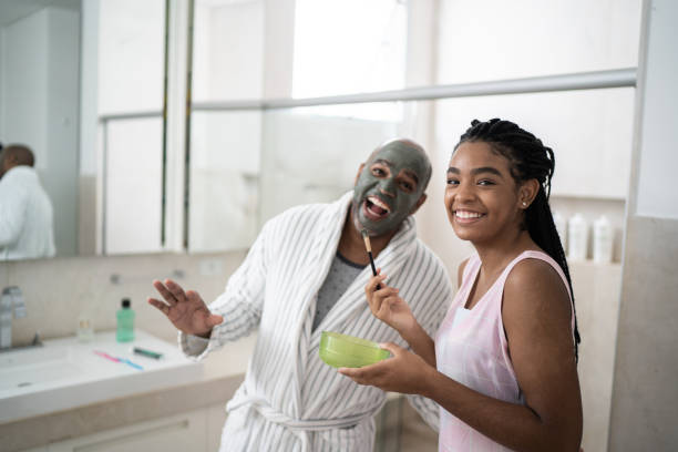 Portrait of teenager girl applying facial mask on her father - clay mud Portrait of teenager girl applying facial mask on her father - clay mud happy fathers day funny stock pictures, royalty-free photos & images