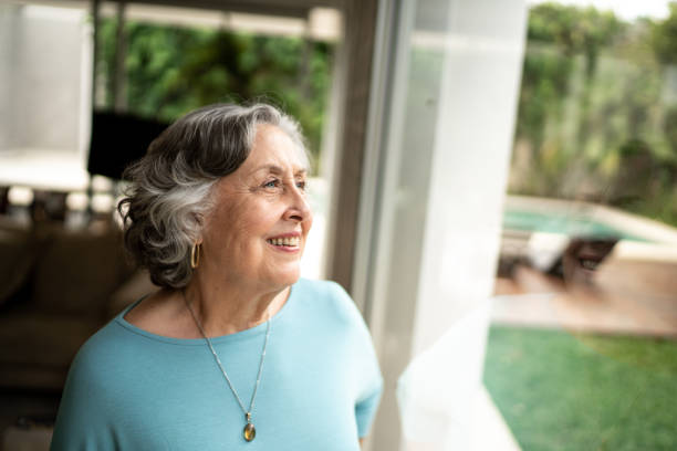 istock Senior woman looking through window at home 1306877023