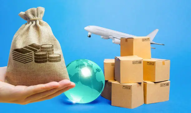 Photo of Money bag, blue globe, cardboard boxes and freight airplane. International world trade. Deliver goods, shipping. Import export freight traffic. Markets globalization.