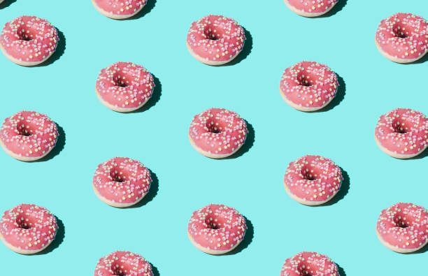 istock Trendy sunlight Summer pattern made with pink doughnut on bright light blue background. Minimal summer concept. 1306881601