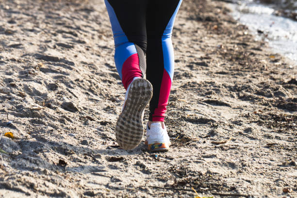 young woman legs run, jogging at the beach