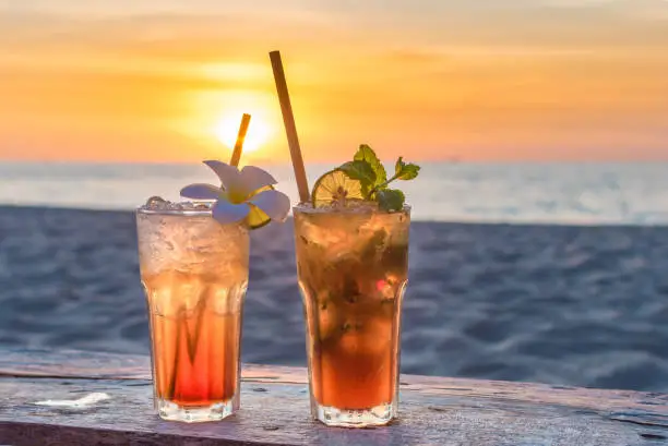 Photo of drinks with blur beach and sunset in background