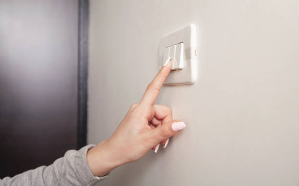istock Female hand turning an electricity light switch on the wall. 1306884846