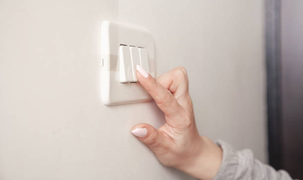 istock Female hand turning an electricity light switch on the wall. 1306884848