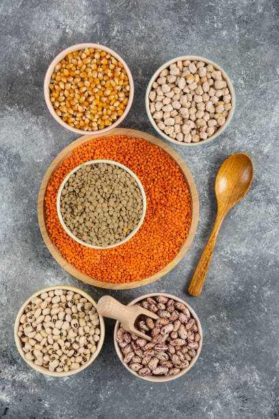 istock Bowls of various uncooked beans, lentils and corns on marble surface 1306887979
