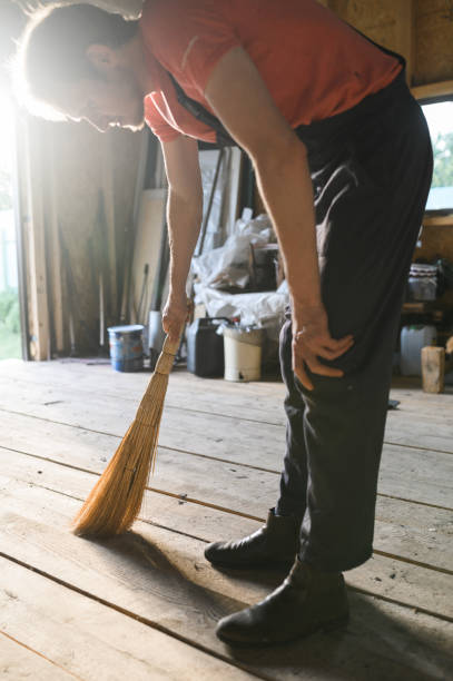 istock man sweeps the wood floor. barn cleaning 1306893531