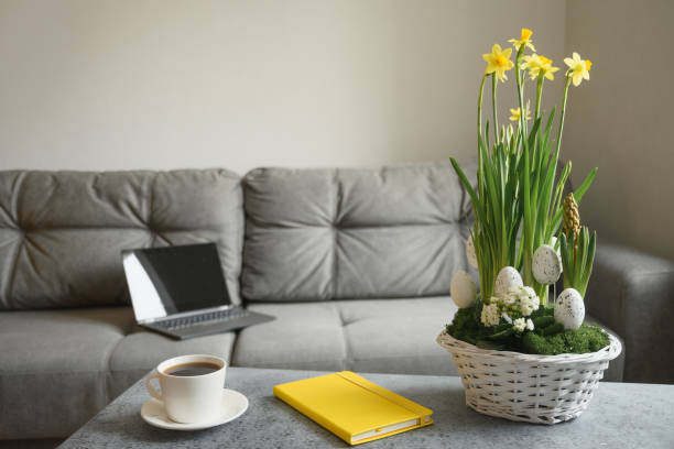 istock Spring home interior in living room with cup of coffee and notebook on sofa. 1306895829