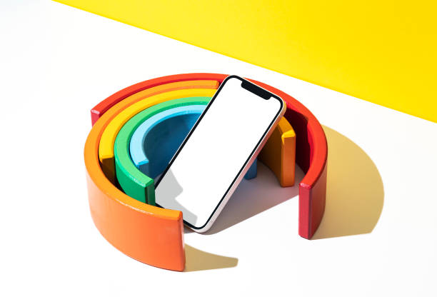 Blank screen smart phone mockup, template with clipping path. Colorful rainbow toy. Vibrant colored arches on yellow and white background.
