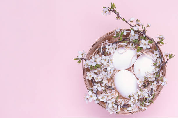 istock White easter eggs in a basket with flowers on a pink background. Horizontal photograph. Top view 1306899254