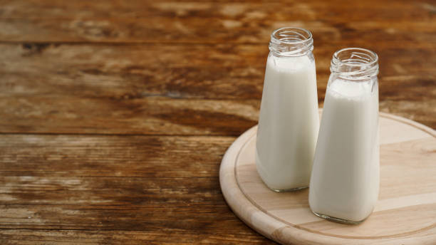 istock Fresh milk in two glass bottles. Wood rustic background 1306899355