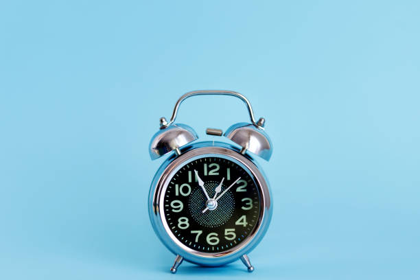 istock Black Vintage Alarm Clock on Blue Background 1306900709