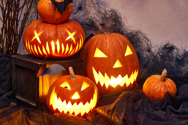 istock Halloween composition of burning pumpkin with bat. Cobwebs branches atmosphere 1306902588