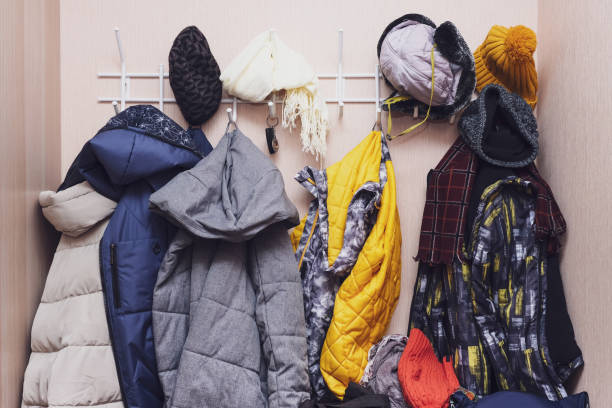 istock Many winter coats and caps, hats hanging in a mess on hooks in a corridor, decluttering warm clothes 1306905726