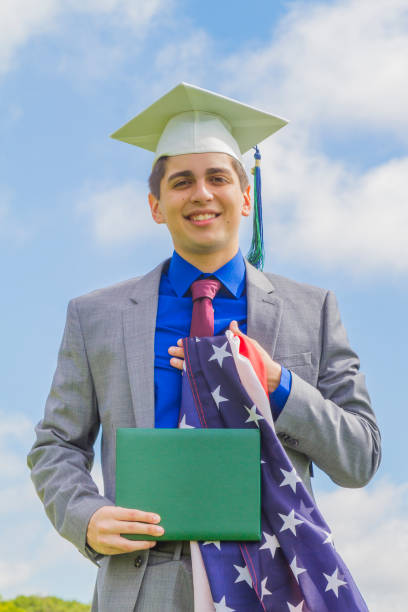 retrato de alegre felicidade belo estudante latino masculino vestindo um vestido e um chapéu, participando de sua cerimônia de formatura nos estados unidos, eua - armed forces latin american and hispanic ethnicity saluting marines - fotografias e filmes do acervo