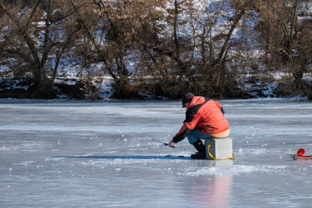 Winter fishing. A fisherman in a red jacket catches a fish Vinnitsa, Ukraine - February 06, 2021: Winter fishing. A fisherman in a red jacket catches a fish vinnytsia stock pictures, royalty-free photos & images