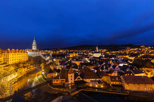 Aerial panorama night view of Český Krumlov old town with the Cesky Krumlov castle and tower in background and Vltava river flowing around, Czech Republic