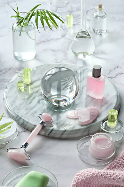 Gua Sha massager and pink quarz face roller on marble stone background. Face care products, glass crystal ball and exotic palm leaves. Towel, skincare tonic, soap, essential oil and serum. gua sha masajeador y rodillo de cara quarz rosa sobre fondo de piedra de mármol. productos para el cuidado de la cara, bola de cristal de vidrio y hojas de palma exóticas. toalla, tónico para el cuidado de la piel, aceite esencial y suero revitalizante