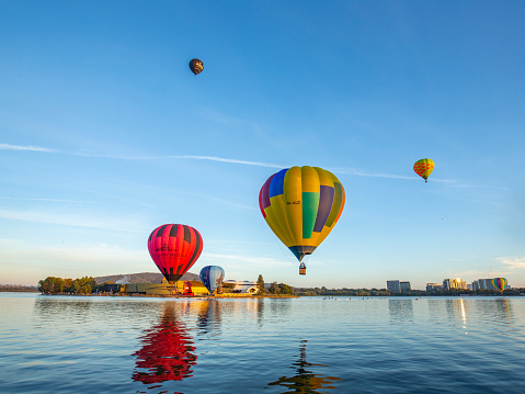Colorful hot air balloons floating over Lake Burley Griffin in Canberra, Australia for the Canberra Balloon Spectacular 2021