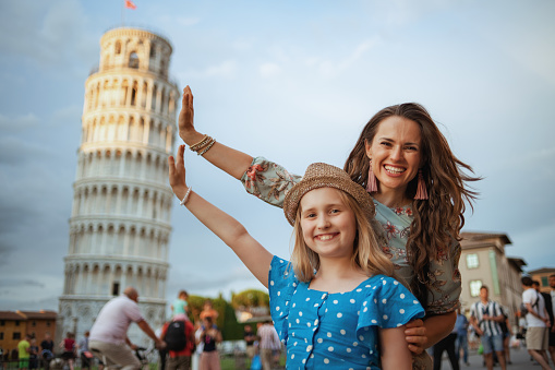 happy mom and child posing at Leaning Tower in Pisa, Italy