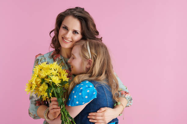 istock smiling elegant mother and daughter hugging on pink 1306919387