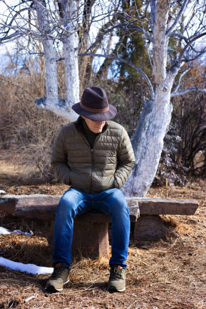 istock Pensive Man Sitting Near Winter Apple Trees Painted White 1306924220