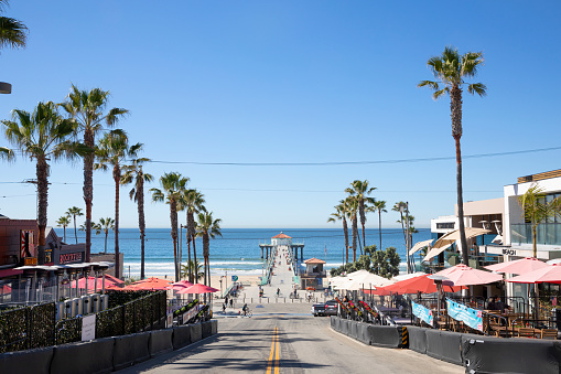Manhattan Beach, California, USA - February 2021: View of Manhattan Beach Boulevard and Manhattan Beach Pier with locals and tourist walking on the pier,