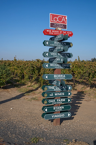 Lodi, California – October 31, 2019: Most rural areas have two road signs that tell you where you are. The rural area surrounding the city of Lodi has signs at intersections directing to you to some of about 85 wineries in the area. Most, such as this one, have more than a dozen wineries and vineyard signs to give you directions.