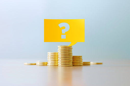 Question mark written yellow speech bubble sitting over coins stacks before defocused background. Horizontal composition with copy space. Great use for budget concepts.