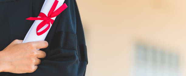 istock Students In Graduation Gowns Showing Diplomas 1306947447