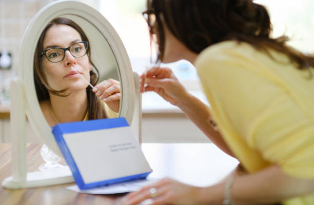 Woman at home using a nasal swab for covid 19 detection A woman at home is using a lateral flow testing kit. antigen photos stock pictures, royalty-free photos & images