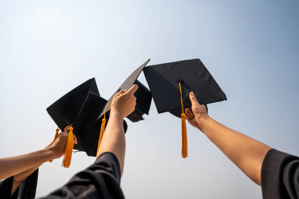 istock graduates student Graduation caps thrown in the Air Blue sky 1306947485
