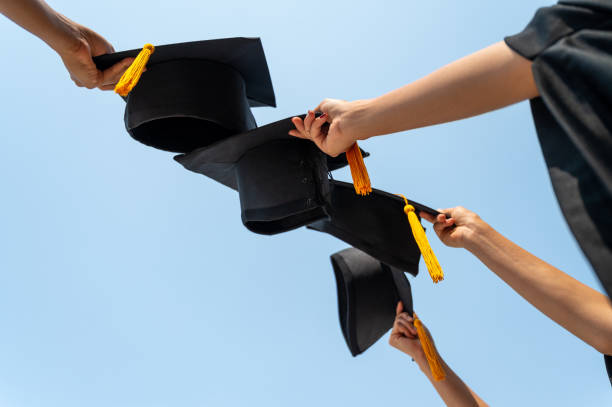 istock graduates student Graduation caps thrown in the Air Blue sky 1306947507