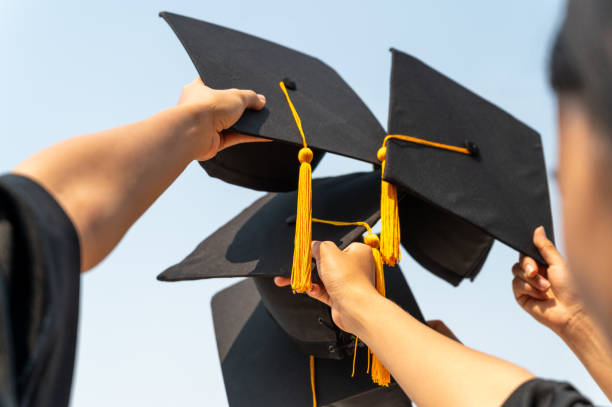 istock graduates student Graduation caps thrown in the Air Blue sky 1306947552